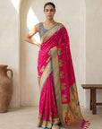 Woman wearing a pink saree with a gold border in an indoor setting