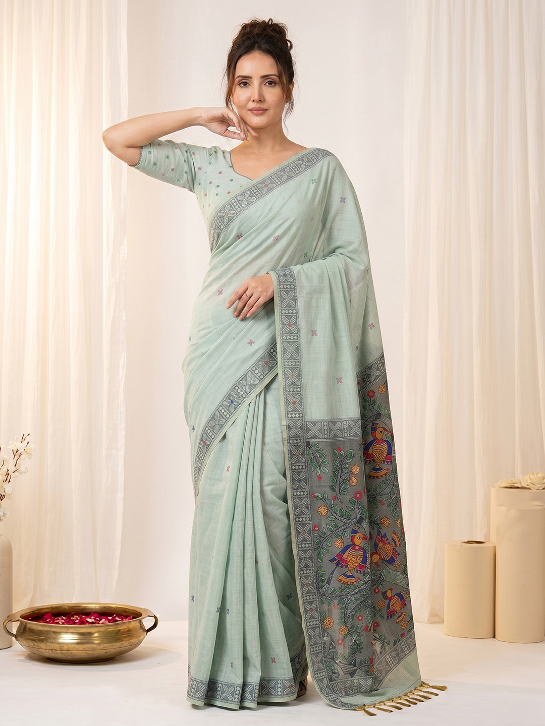 Woman wearing a light blue saree with a floral border against a white background