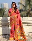 Woman in a pink and orange saree with floral patterns standing outdoors.