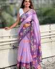 Woman wearing a purple saree with floral patterns standing outdoors.