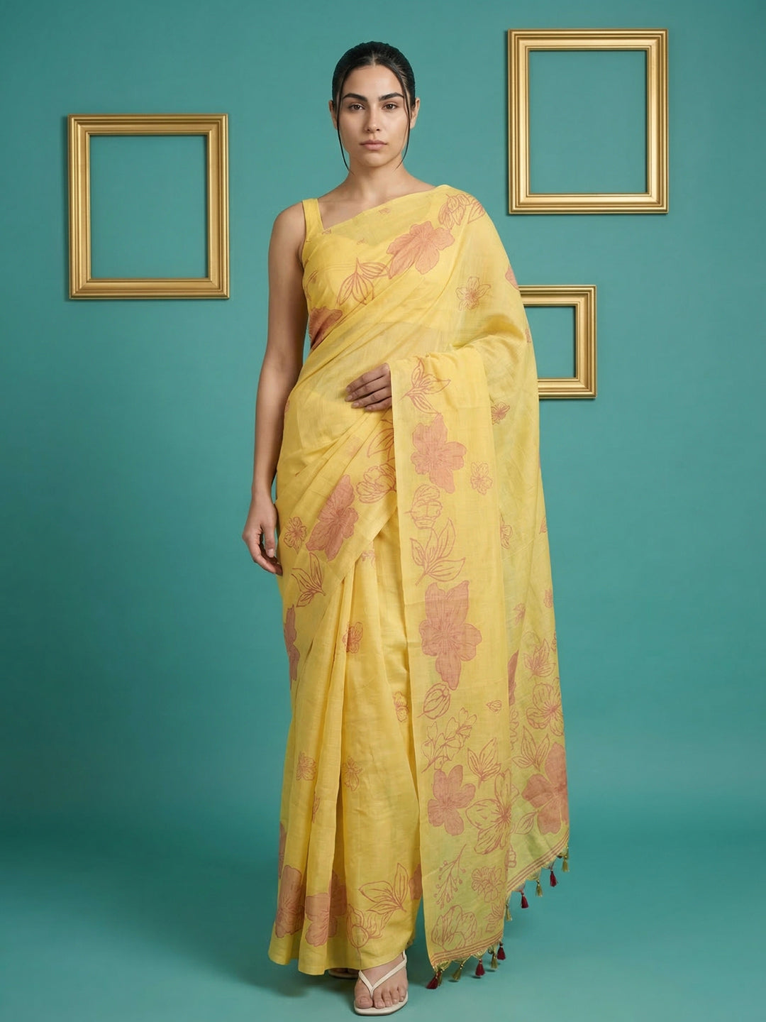 Woman wearing a yellow saree with floral patterns against a teal background
