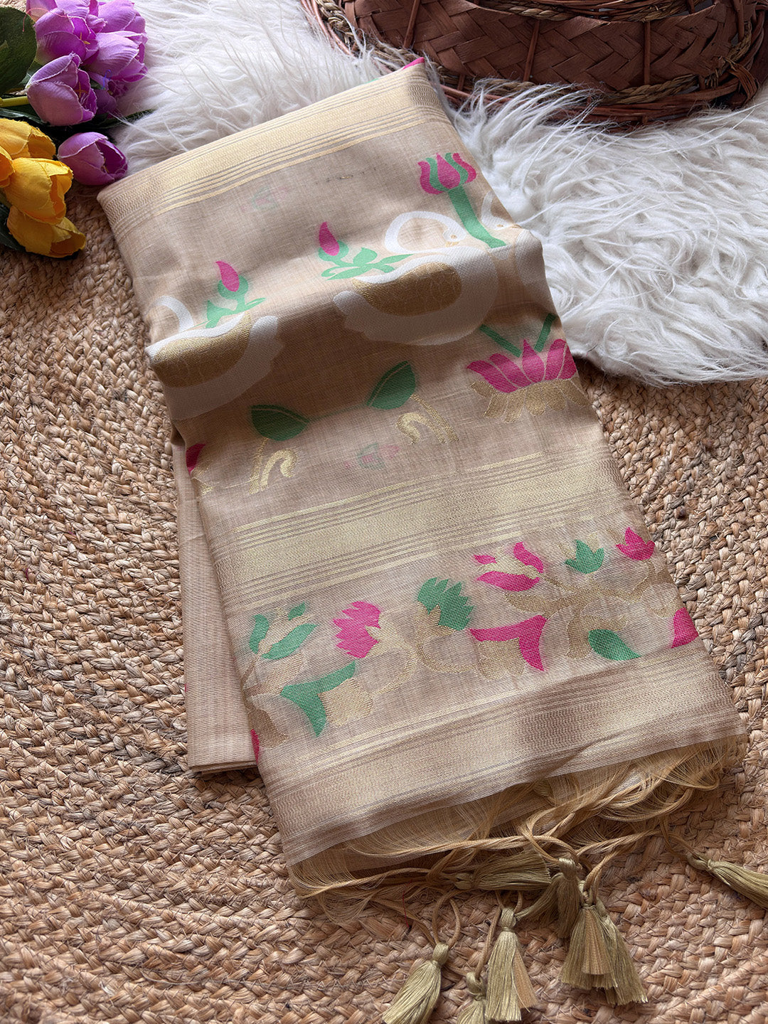 Beige scarf with floral patterns on a textured surface with flowers and a basket in the background