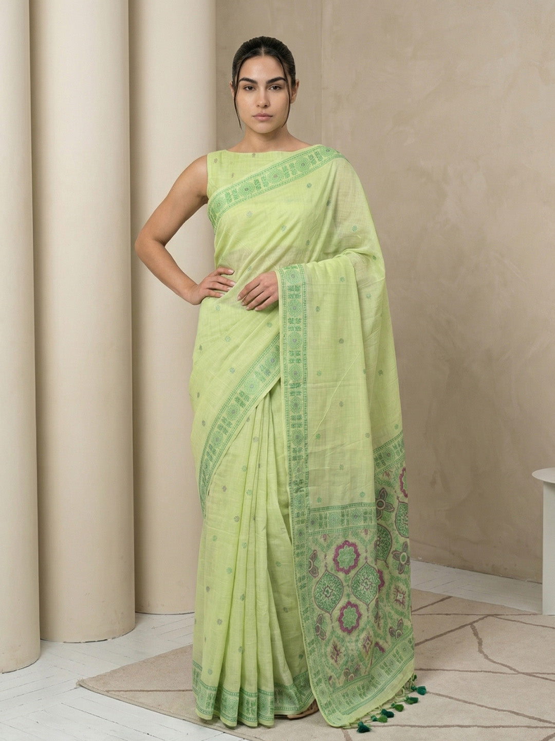 Woman wearing a light green saree with a beige background