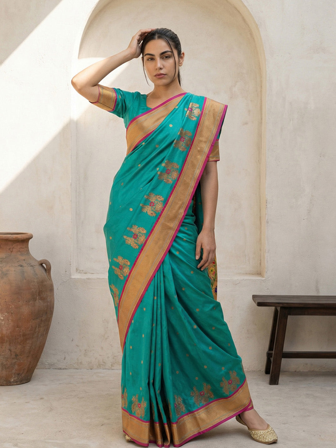 Woman wearing a green saree with gold border in an indoor setting